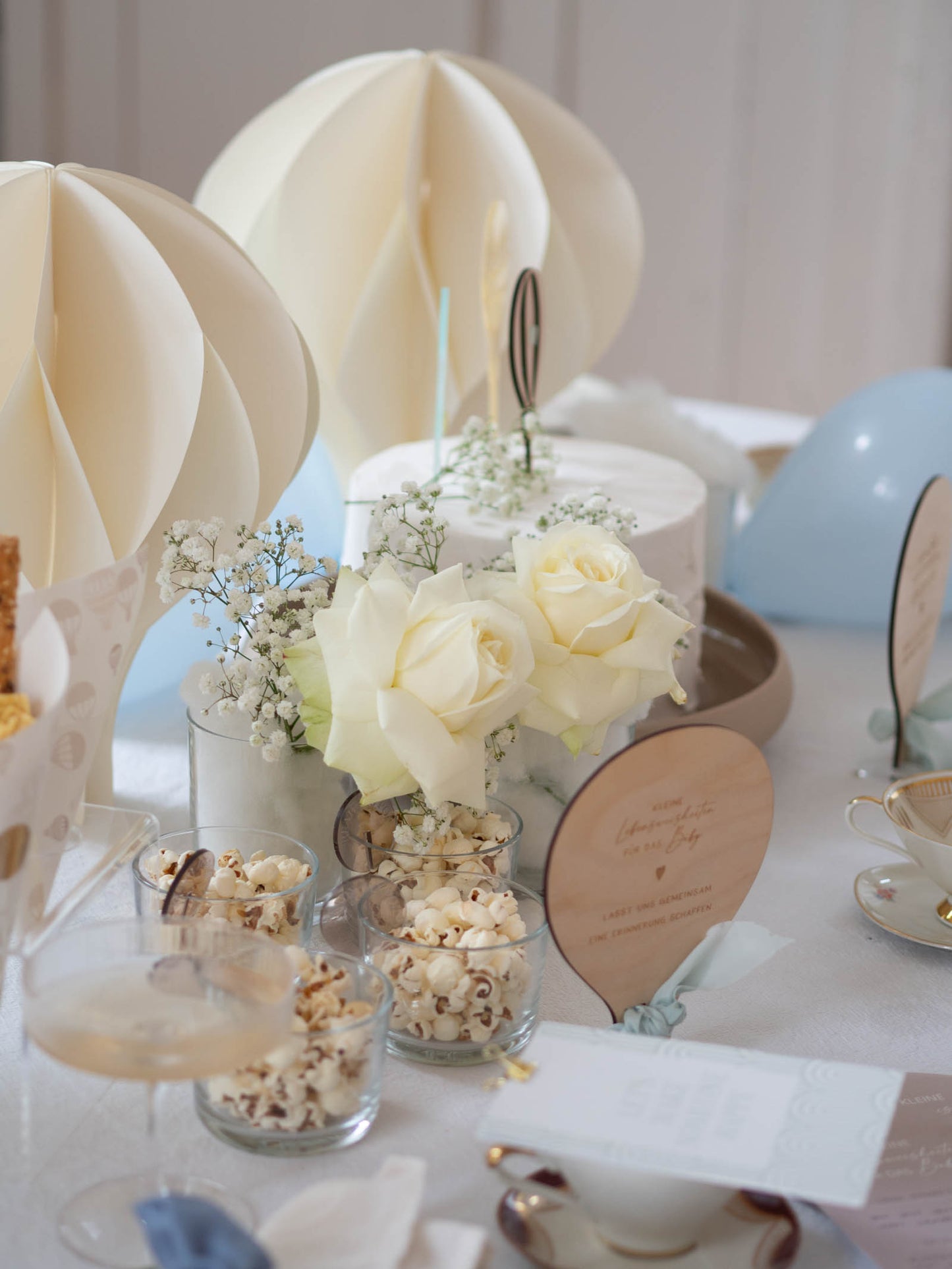 Gedeckter Tisch einer Babyparty zum Thema Heißluftballon mit weißen Rosen und blauen Luftballons