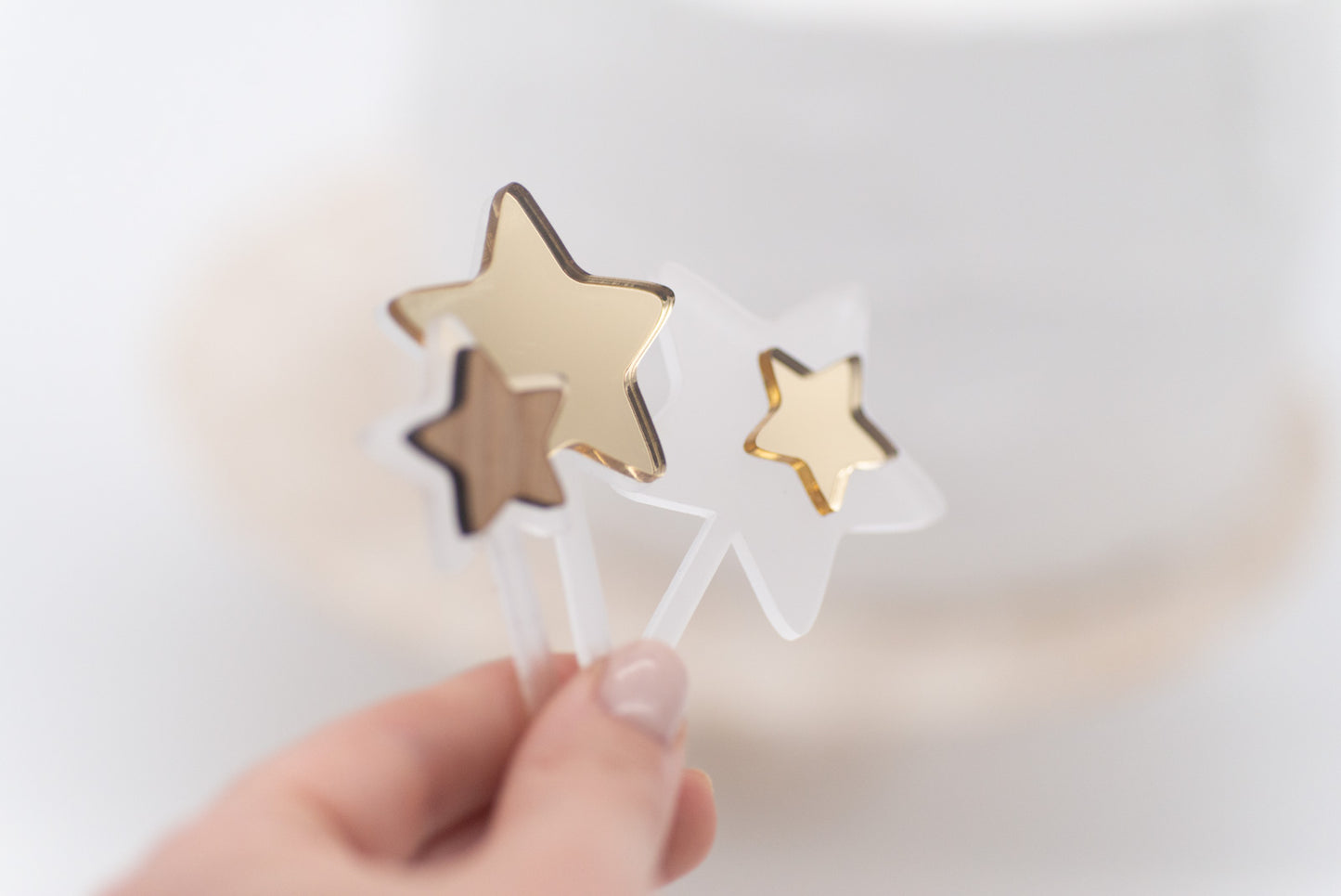 Set aus 3 Caketoppern in Sternenform aus unterschiedlichen Materialien gehalten von einer Hand