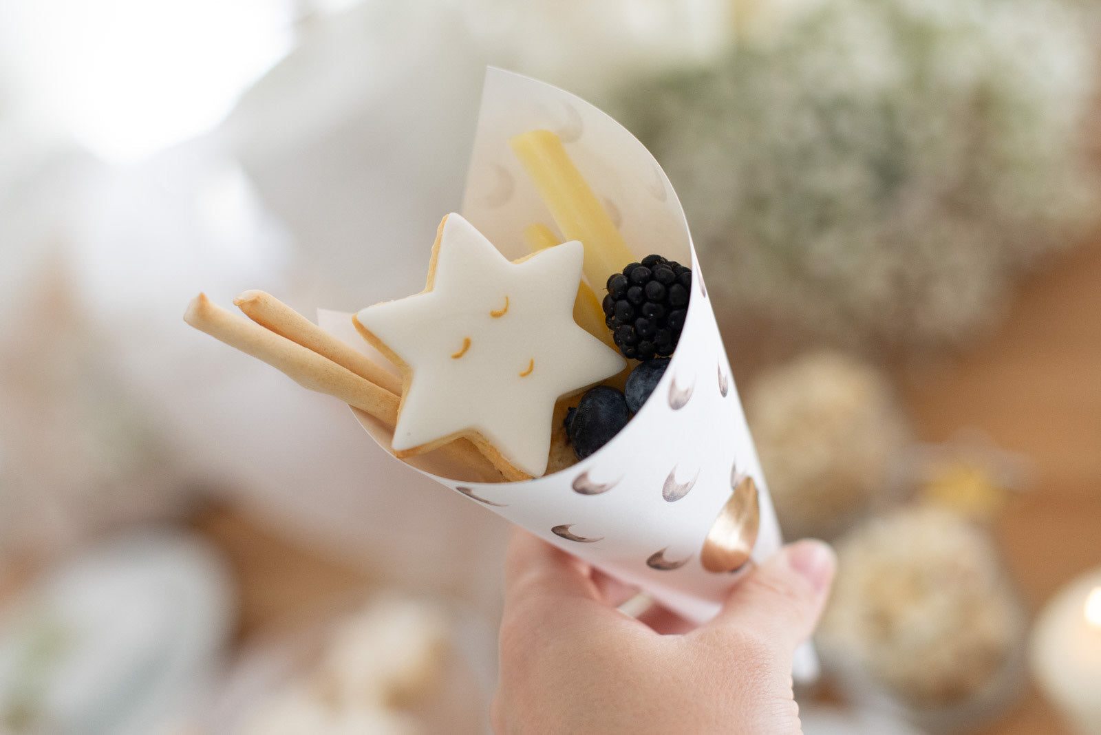 Gefüllte Snacktüte mit lächelndem Stern als Babyparty Buffet Idee, gehalten von einer Hand