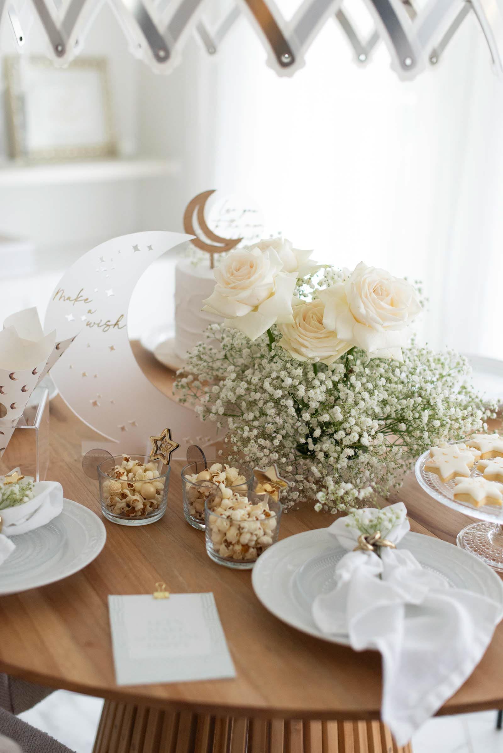 Gedeckter Tisch einer Babyparty zum Thema Mond mit weißen Rosen