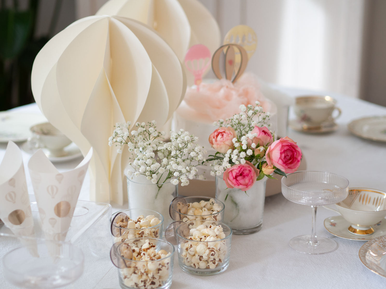 Gedeckter Tisch einer Babyparty zum Thema Heißluftballon mit rosa Blumen