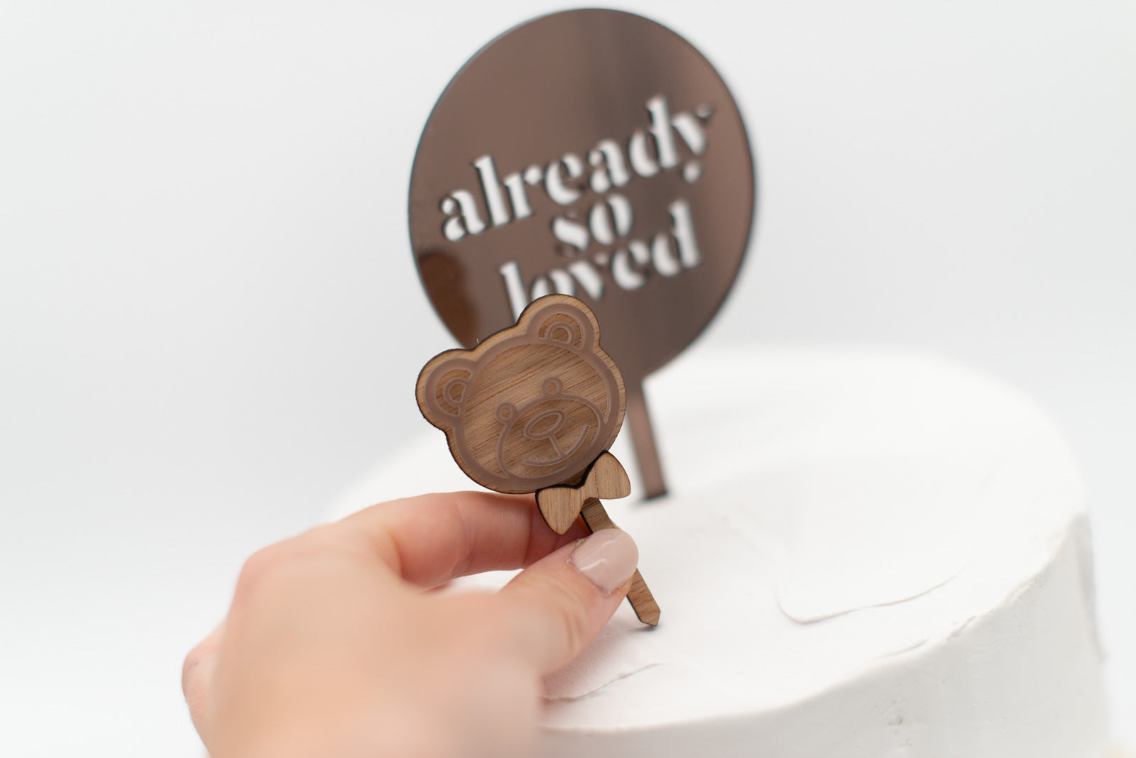 Hand steckt Teddy Caketopper in Kuchen für Babyparty