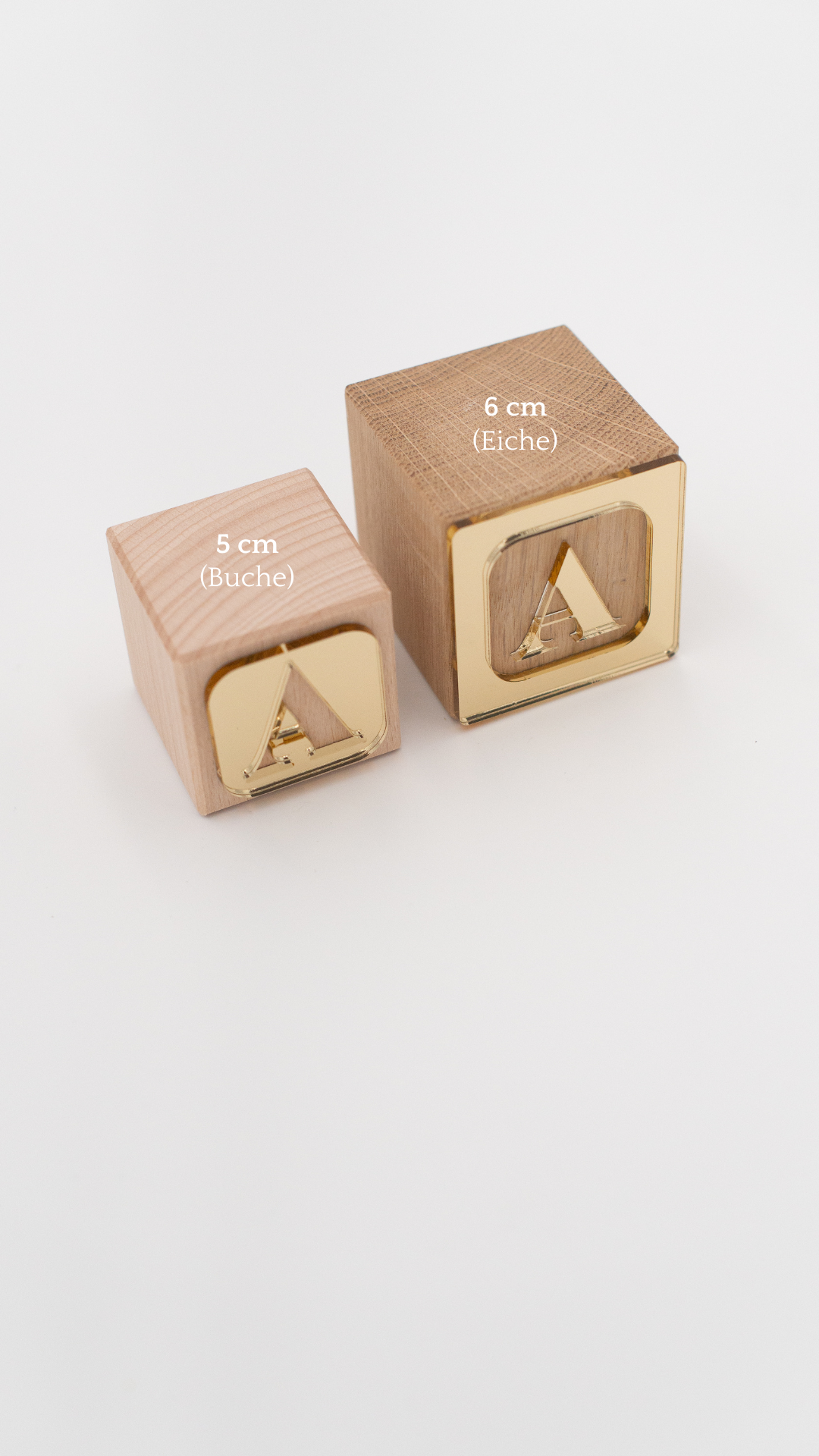 Größenvergleich von 2 Holzwürfeln mit goldenen Buchstaben und unterschiedlichen Materialien