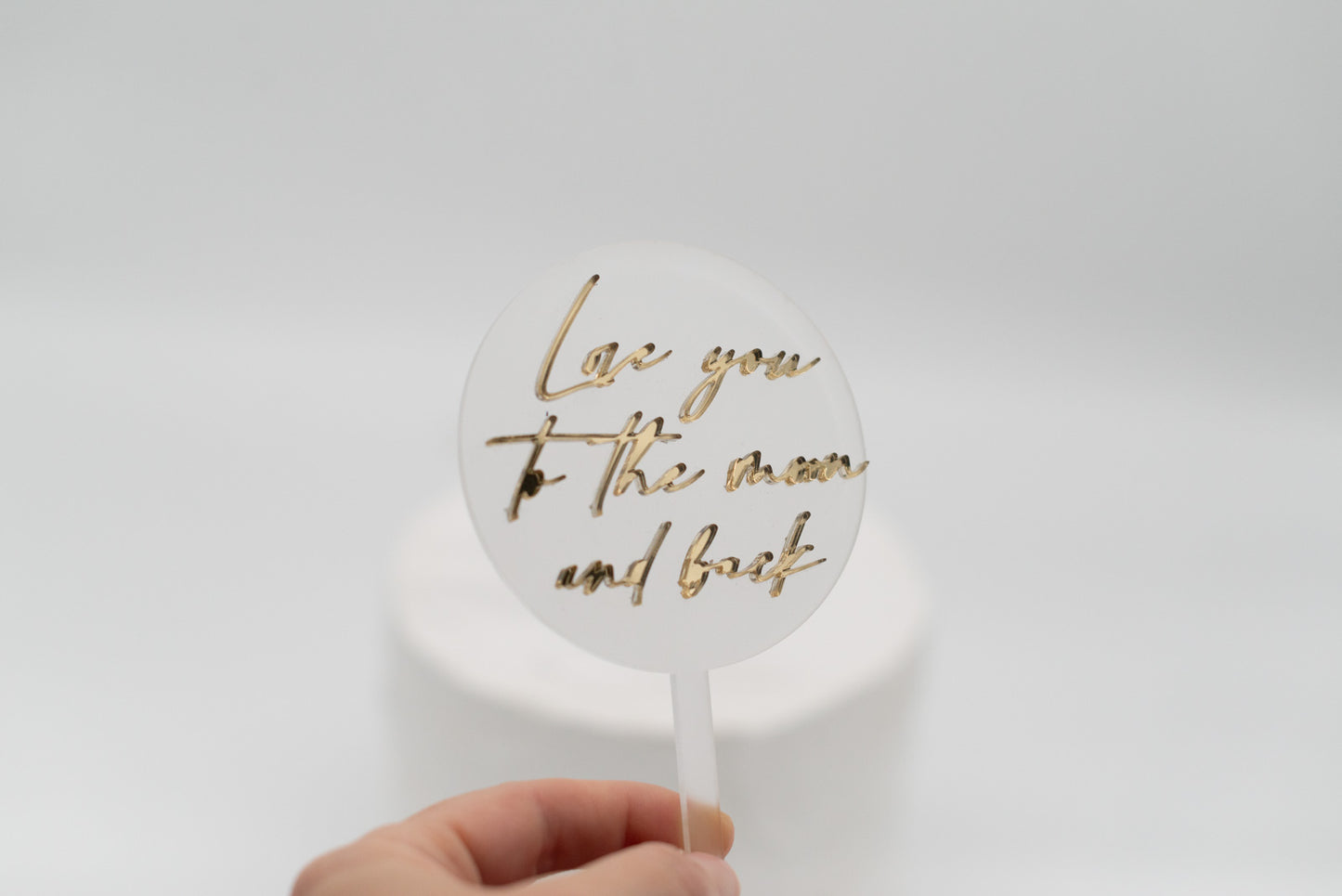 Caketopper gehalten von einer Hand mit goldenem Spruch over the moon