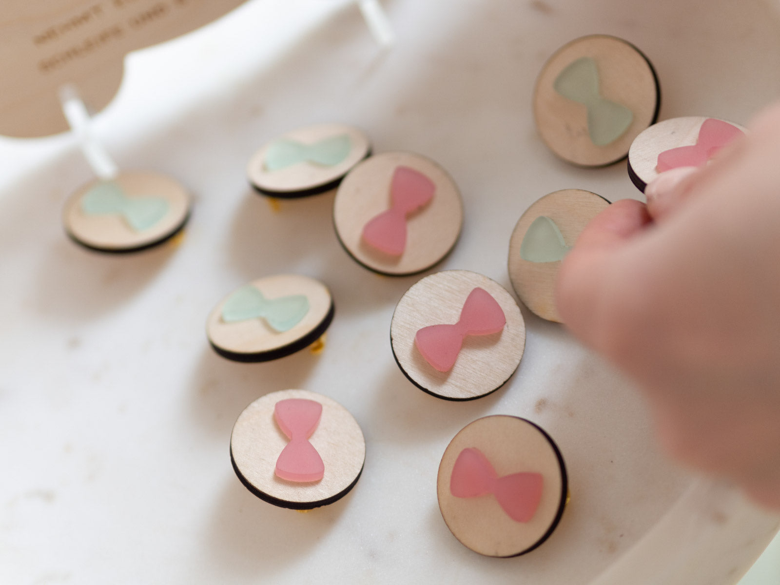 Hand greift Babyparty Spiel Button mit rosa Schleife