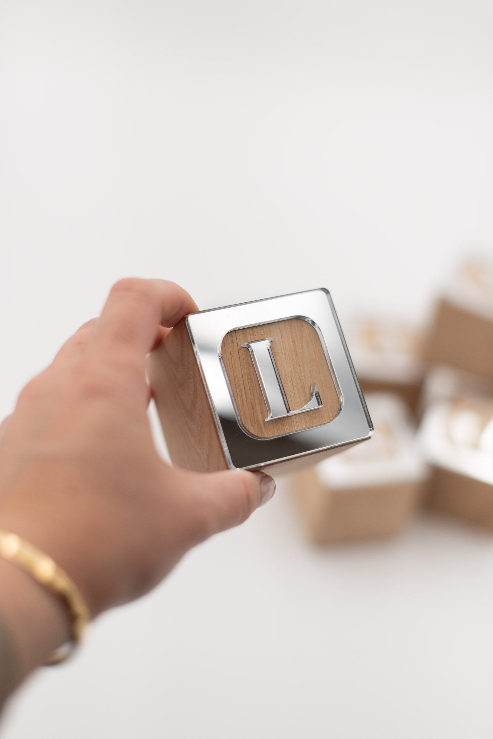 Hand hält Holzwürfel mit Buchstaben L in silber